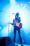 man with electric guitar standing on stage