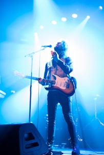 man with electric guitar standing on stage
