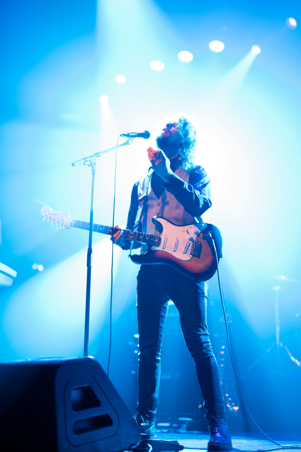 man with electric guitar standing on stage