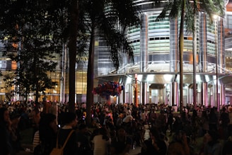 A vibrant crowd enjoying an outdoor event at a modern architectural venue.