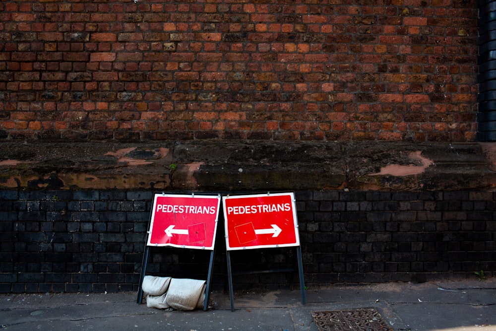 two pedestrians signs beside brown brick building