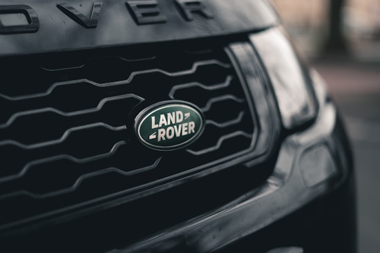 Close-up of a Land Rover grille, showcasing the distinct logo with a dark, textured background adding depth.