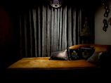 An intimate setting featuring a vintage chaise lounge with dark red satin cushions.