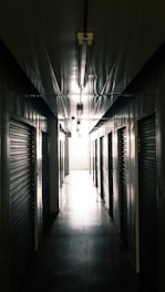A dimly lit corridor bathed in red emergency lights, with heavy steel doors sealed shut.