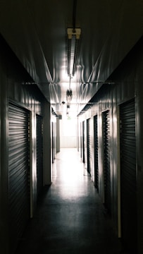 A dimly lit corridor bathed in red emergency lights, with heavy steel doors sealed shut.
