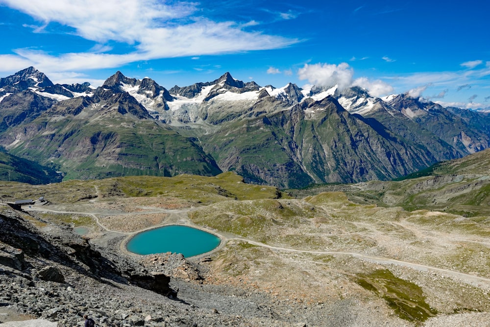 pond, mountains, and field during day