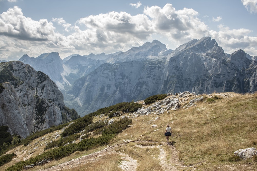 person walking on grass field near mountains during day