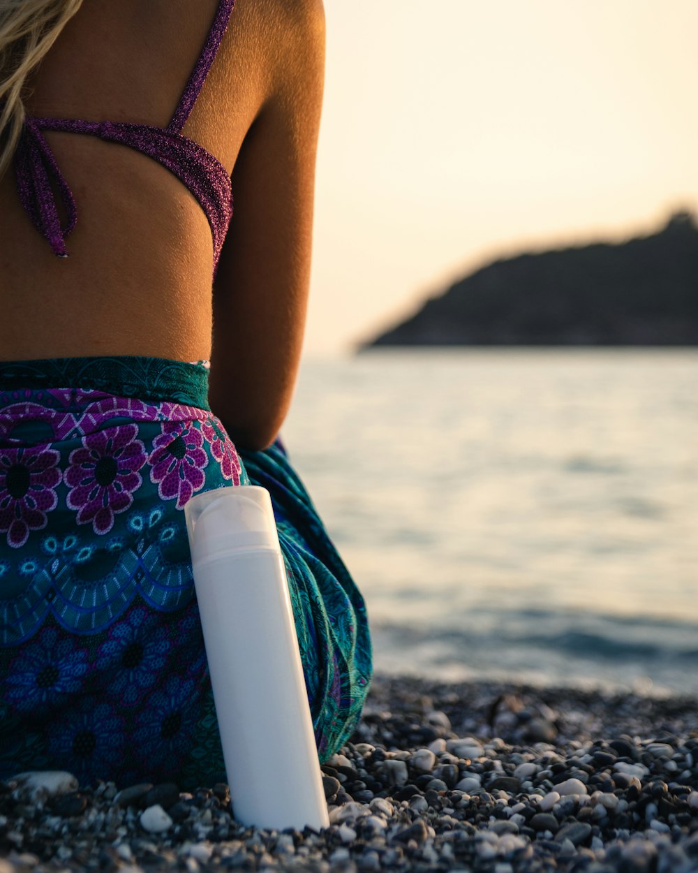 femme assise sur le rivage rocheux pendant la journée