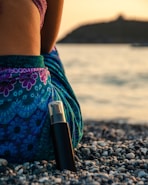 black bottle leaning on woman sitting on rocky shore during day