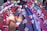 An umbrella is adorned with various colorful ribbons, bows, flowers, and small flags featuring a blue canton with a white sun. The decorations include red, white, and blue elements, as well as tassels and small cartoon figures. The items are neatly arranged in patterned rows across the umbrella's surface.