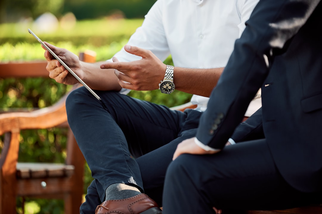 two people sitting during day, two businessmen having a meeting in the park
