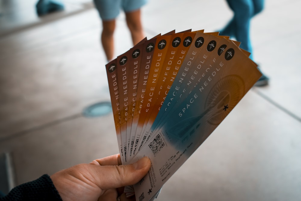 person holding brown, blue, and white tickets