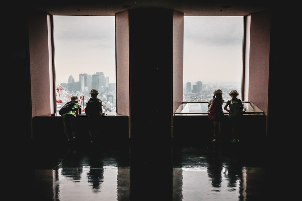 four children looking out the window of a building during day