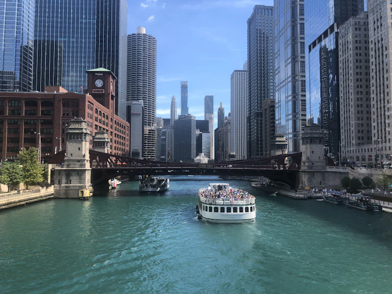 A river architecture tour boat full of passengers cruising past downtown Chicago buildings