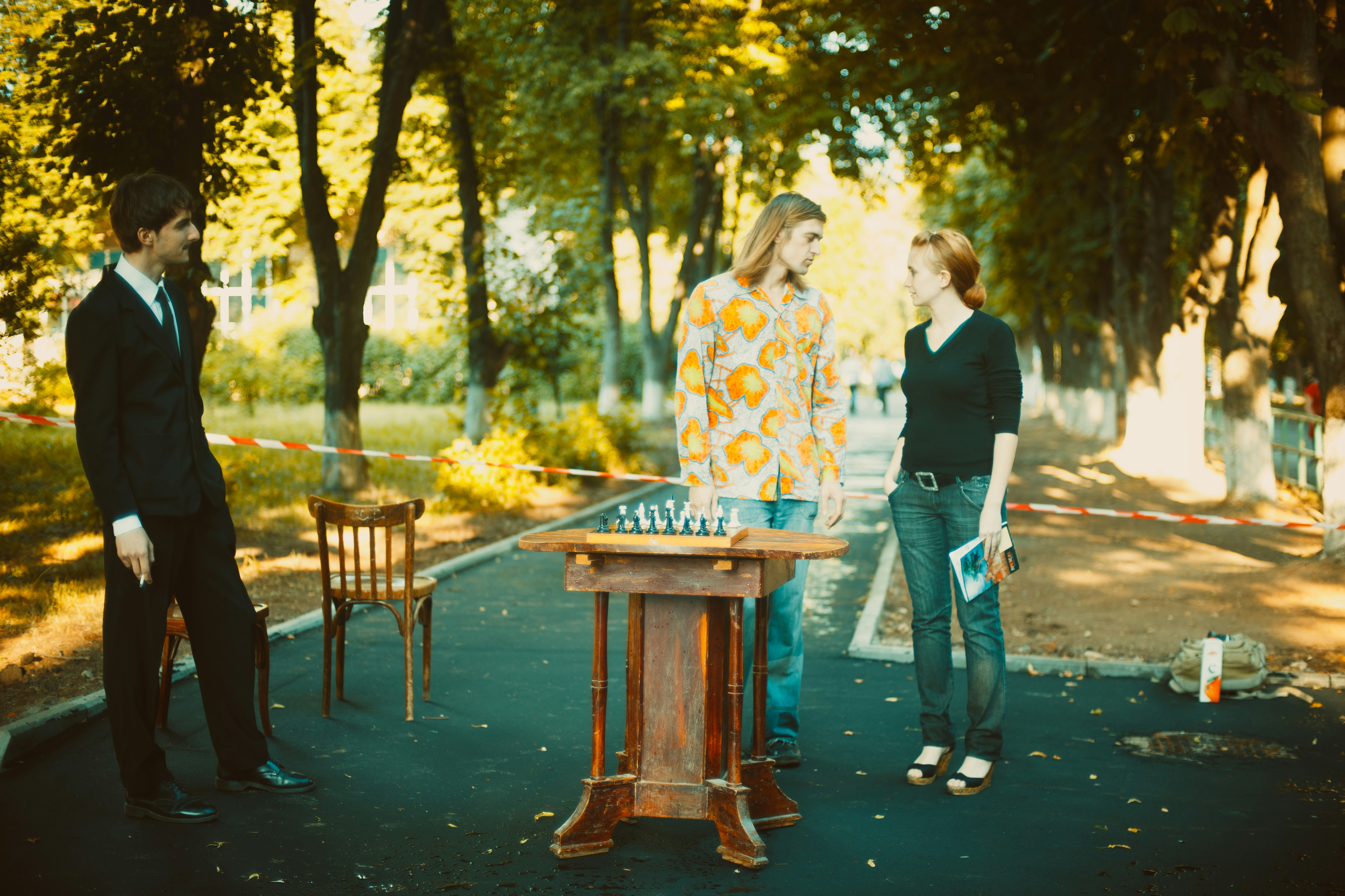 three people standing near table and trees during day