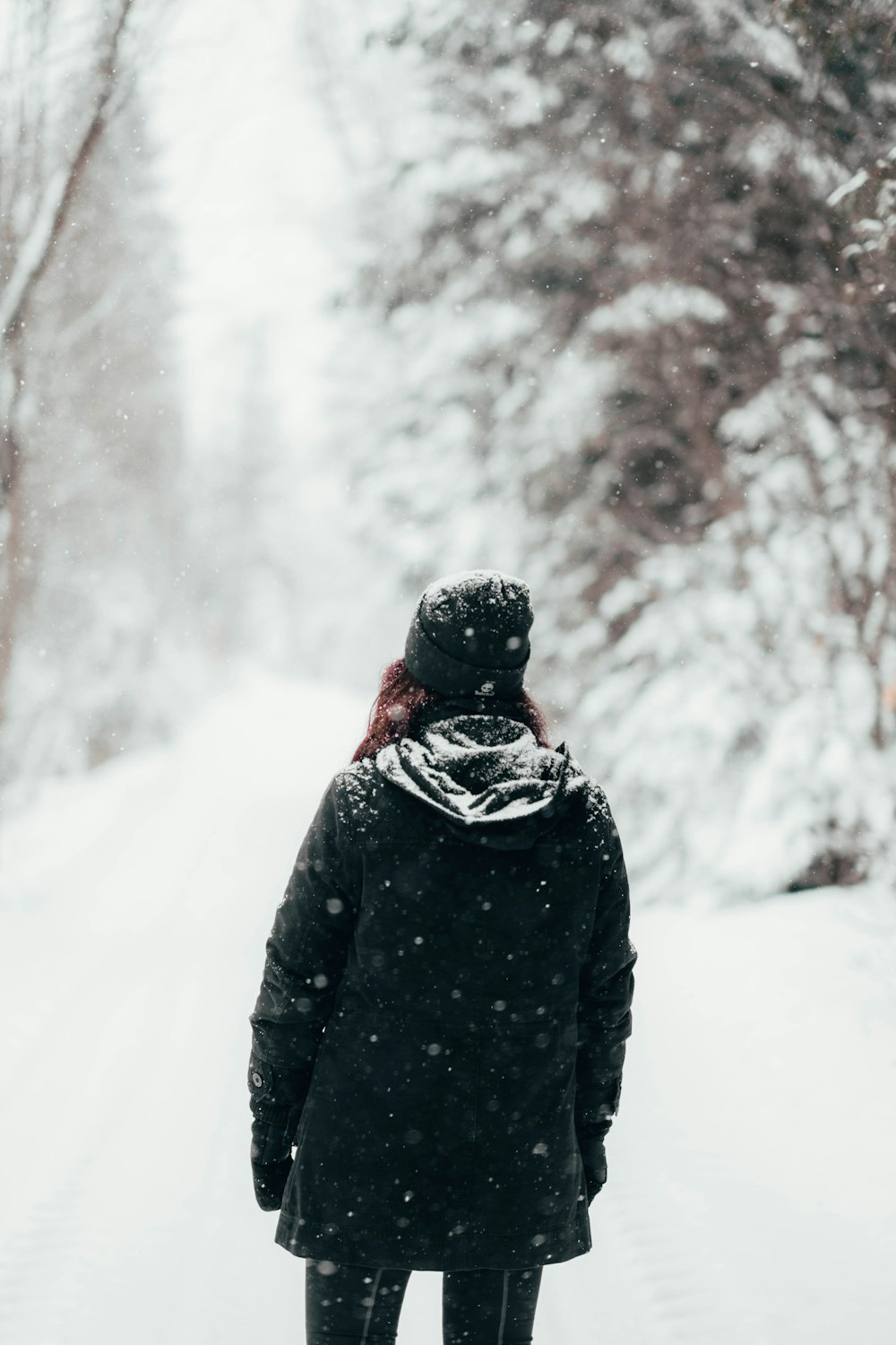 woman standing on snow wearing black winter coat during daytime