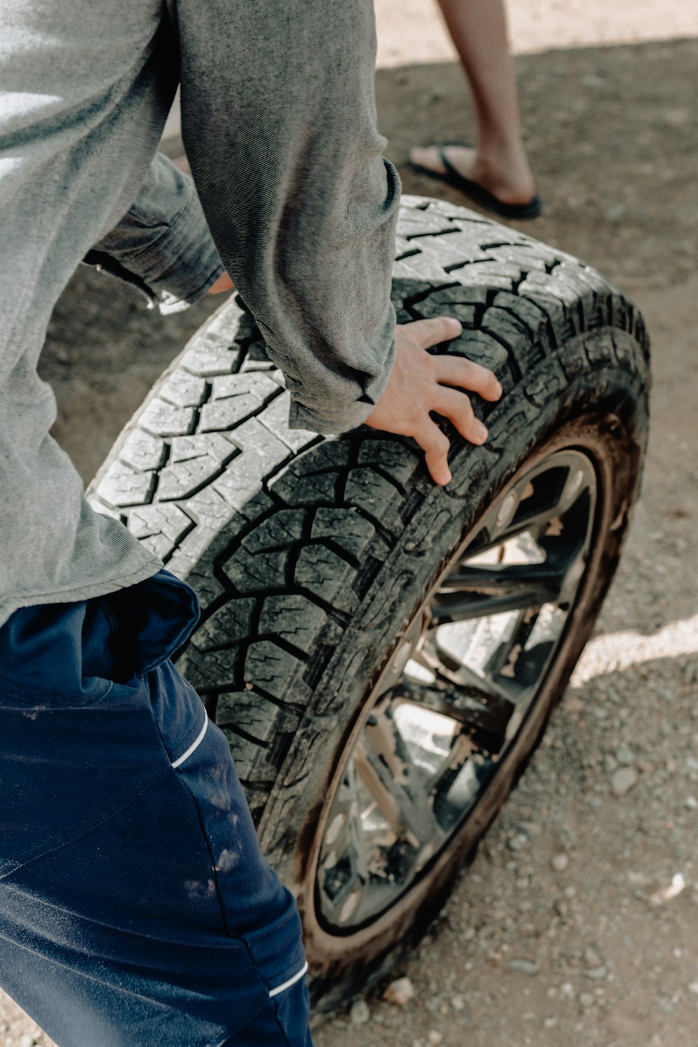 person holding vehicle wheel and rim