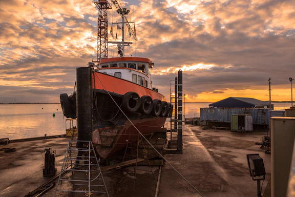 A calm offshore vessel docked at sunset with crew members preparing for maintenance.