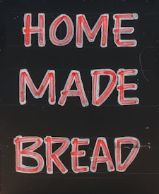A sign with the words 'HOME MADE BREAD' written in large, bold red and white letters against a dark background.