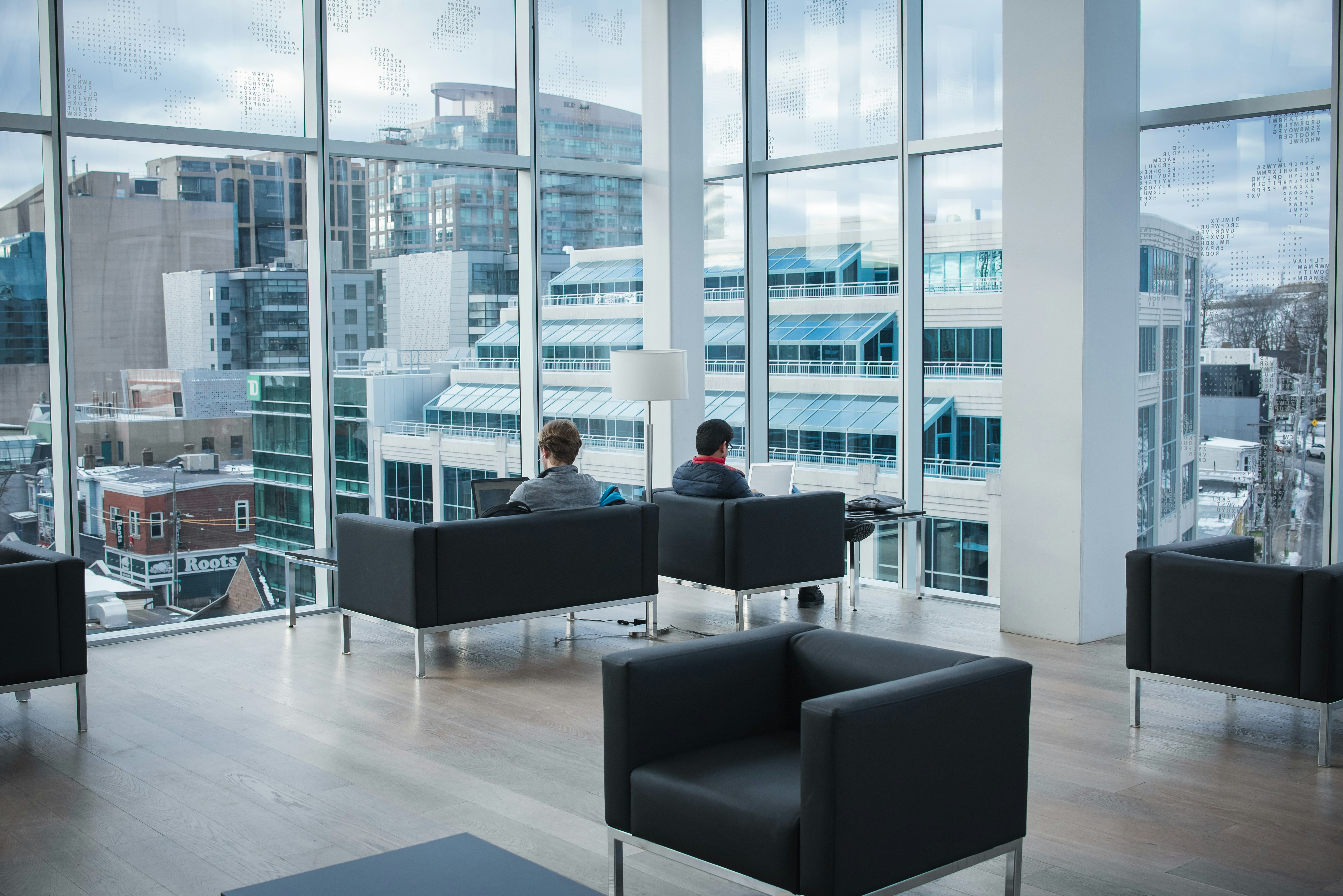 two person sitting on black sofa beside window