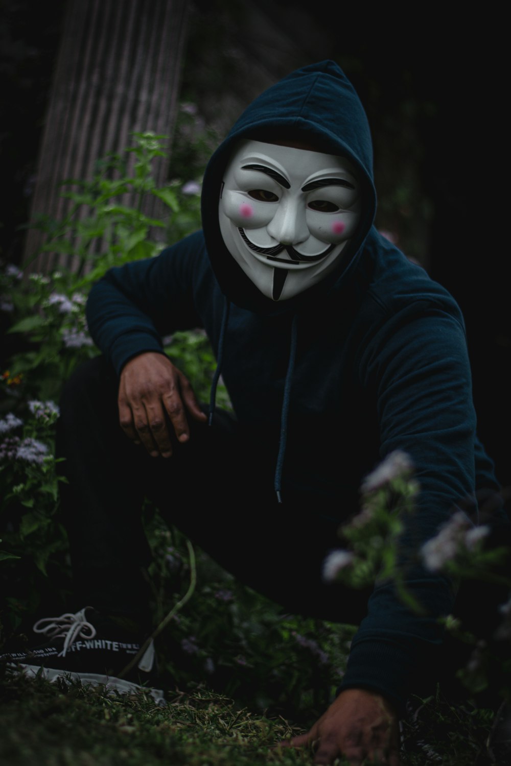 man sitting and wearing Guy Fawkes mask