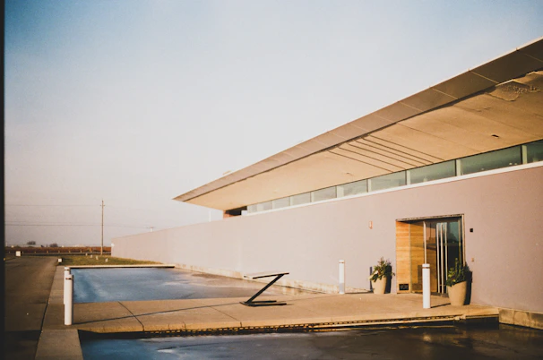 A minimalist luxury home facade featuring clean lines and a reflective water feature in front.