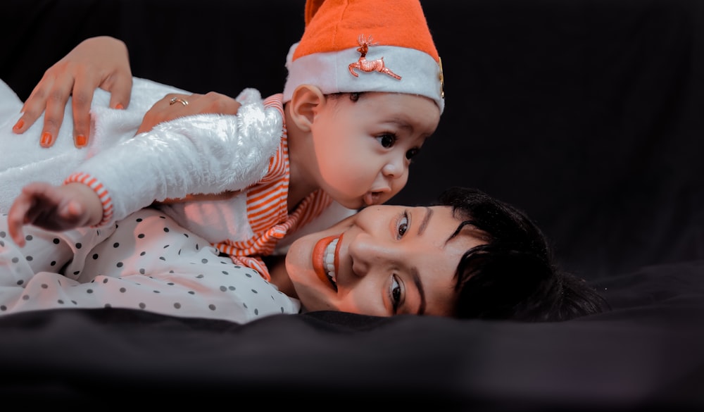 woman hugging baby while lying on bed