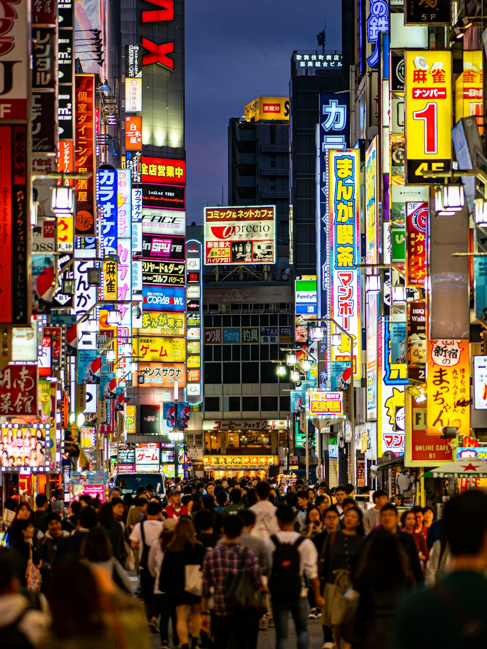 crowd walking on street with lighted signs at night