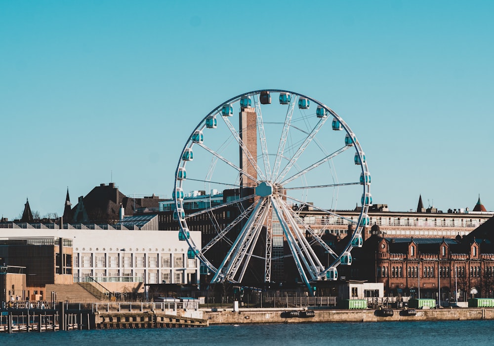 Ferris wheel near buildings facing body of water