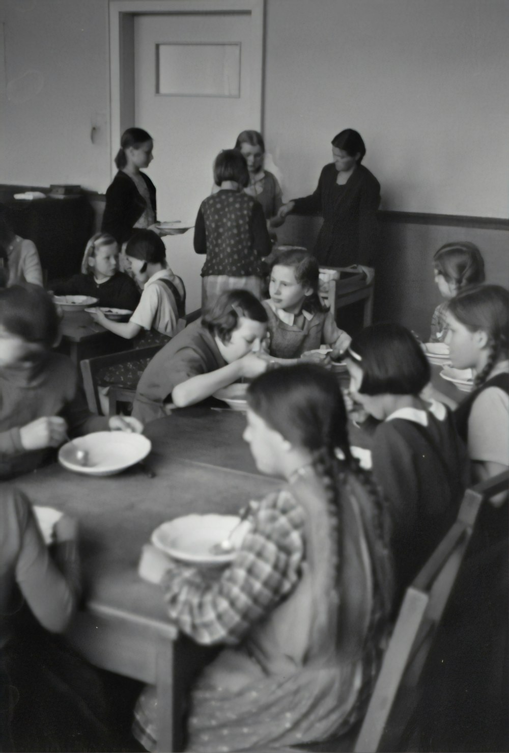 grayscale photography of children sitting while eating near table