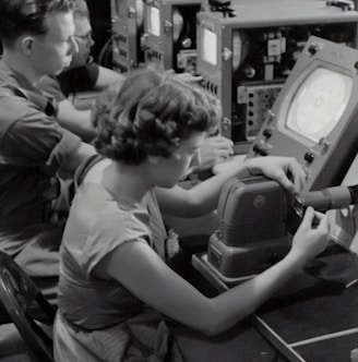 grayscale photography of three people sitting near monitors