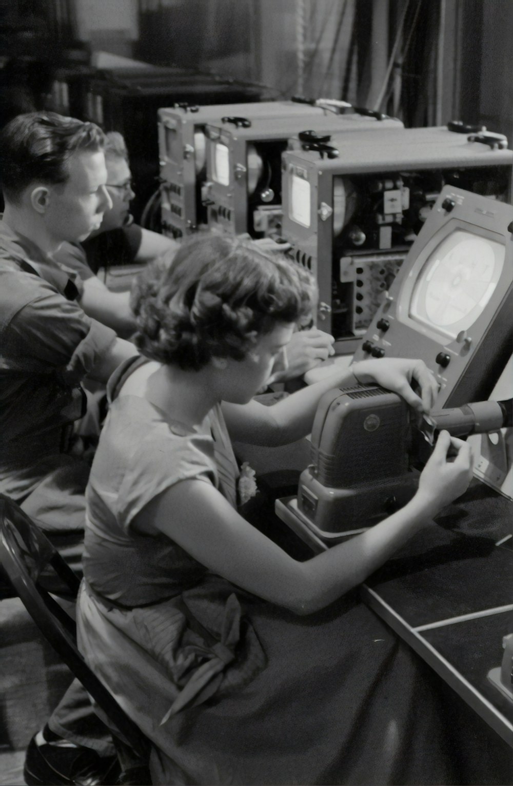 grayscale photography of three people sitting near monitors