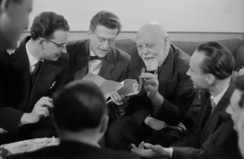 grayscale photography of group of men sitting and chatting