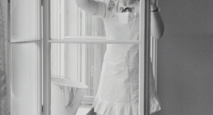 grayscale photography of woman cleaning glass window