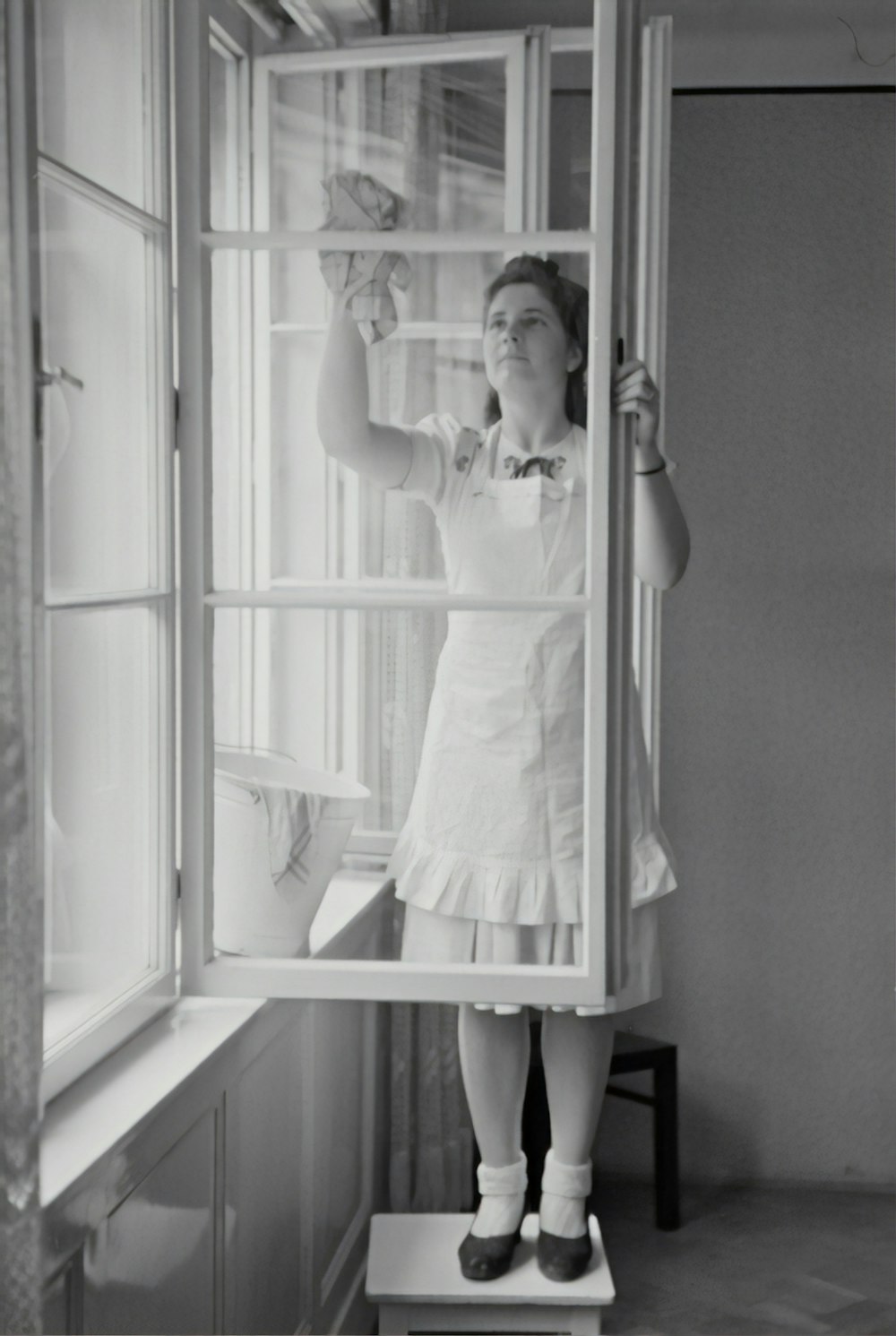 grayscale photography of woman cleaning glass window