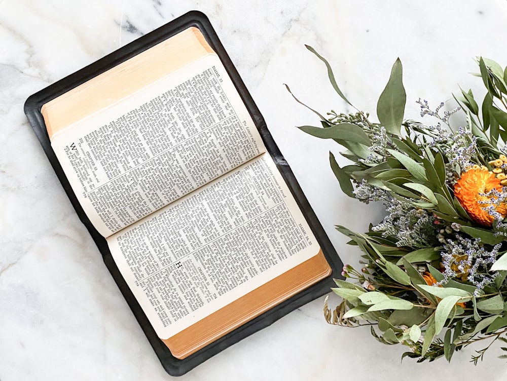 opened bible book beside flowers