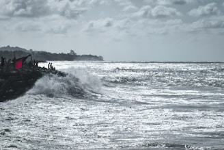 Researchers measuring wave impacts on a rocky shoreline during a storm.