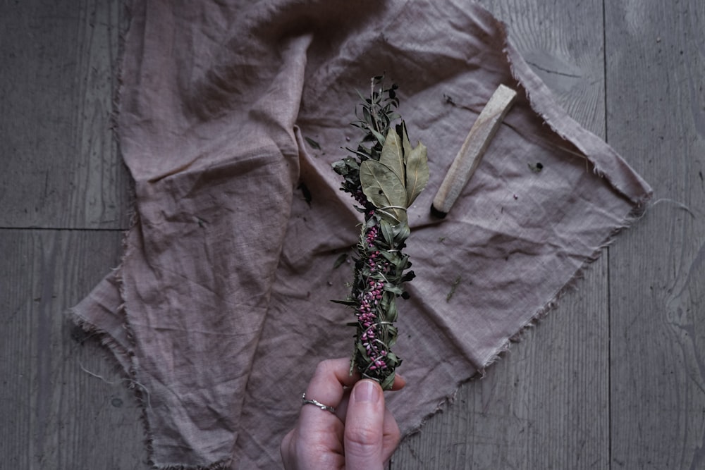 a person holding a flower on top of a piece of paper