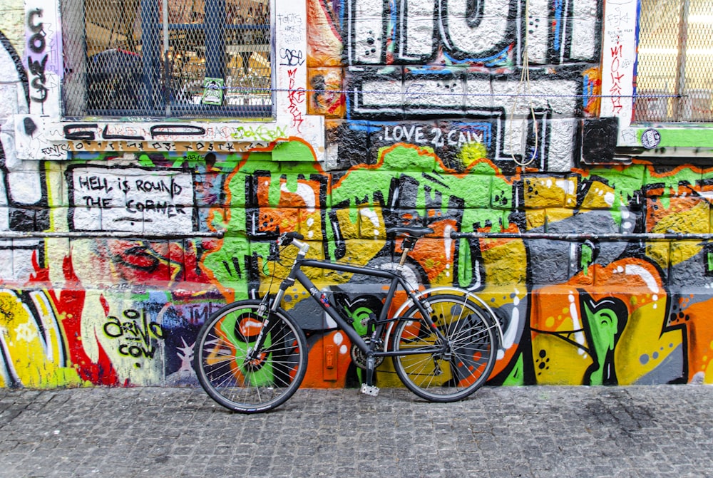 black bicycle parked beside wall with graffiti