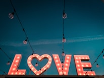 Large 3D illuminated gold letters spelling 'LOVE' shining warmly in a chic event space.