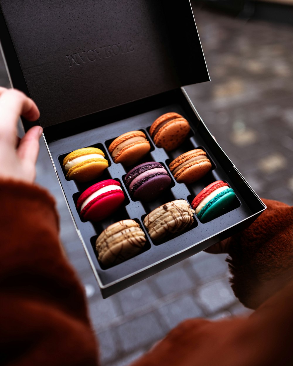 person holding box of French macaroons