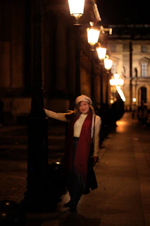 An evening cityscape with a person in Lumina Apparel standing by a glowing streetlamp.