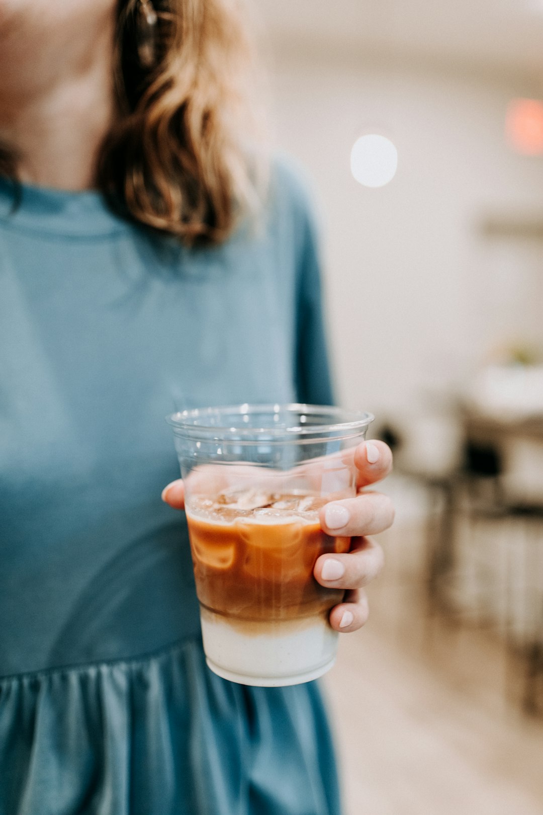 selective focus photography of woman while holding clear plastic cup