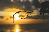 An artistic shot of glasses reflecting a city skyline at sunset.