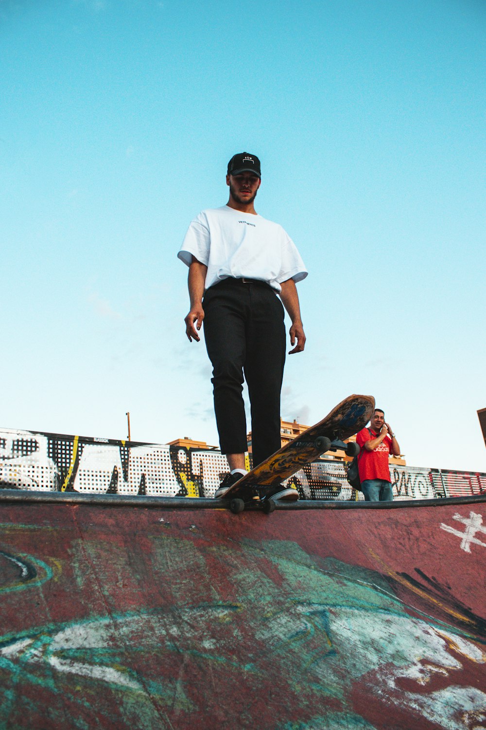 man wearing white shirt and black pants standing on skateboard ramp