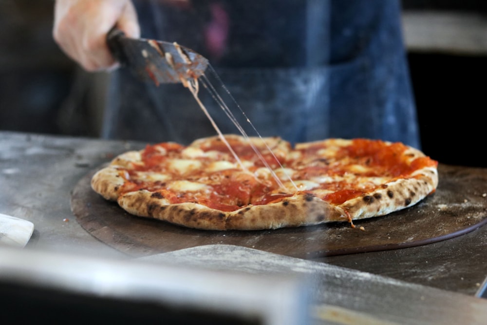 person slicing pizza