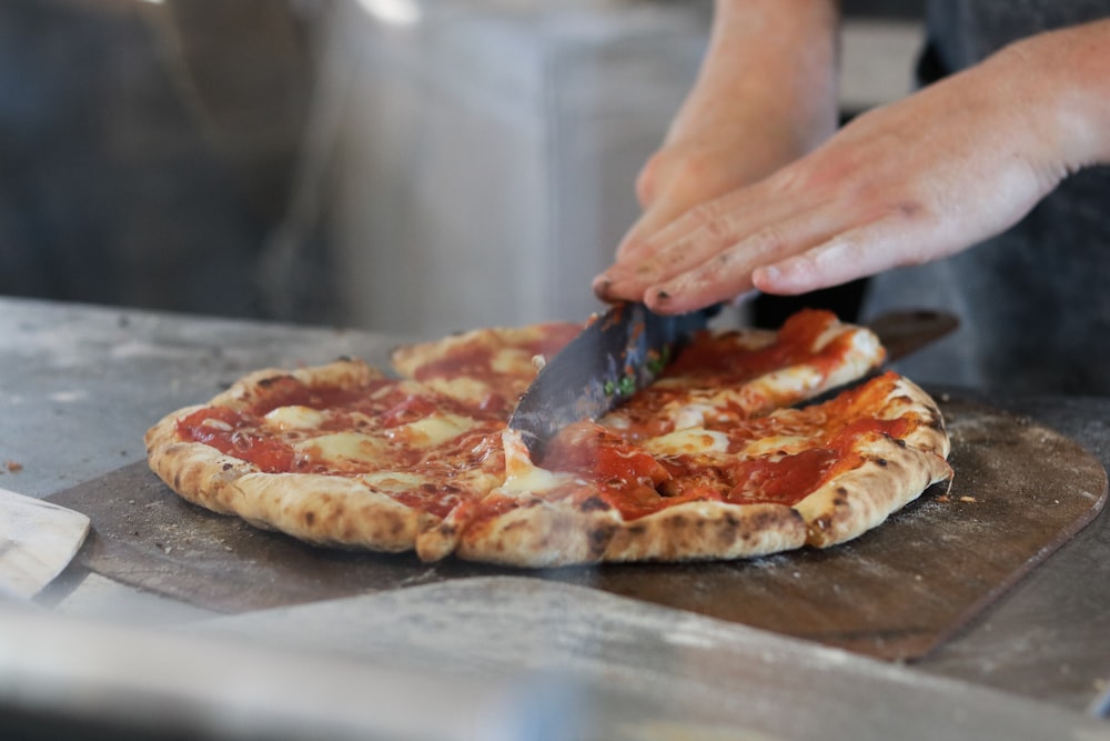 person slicing pizza