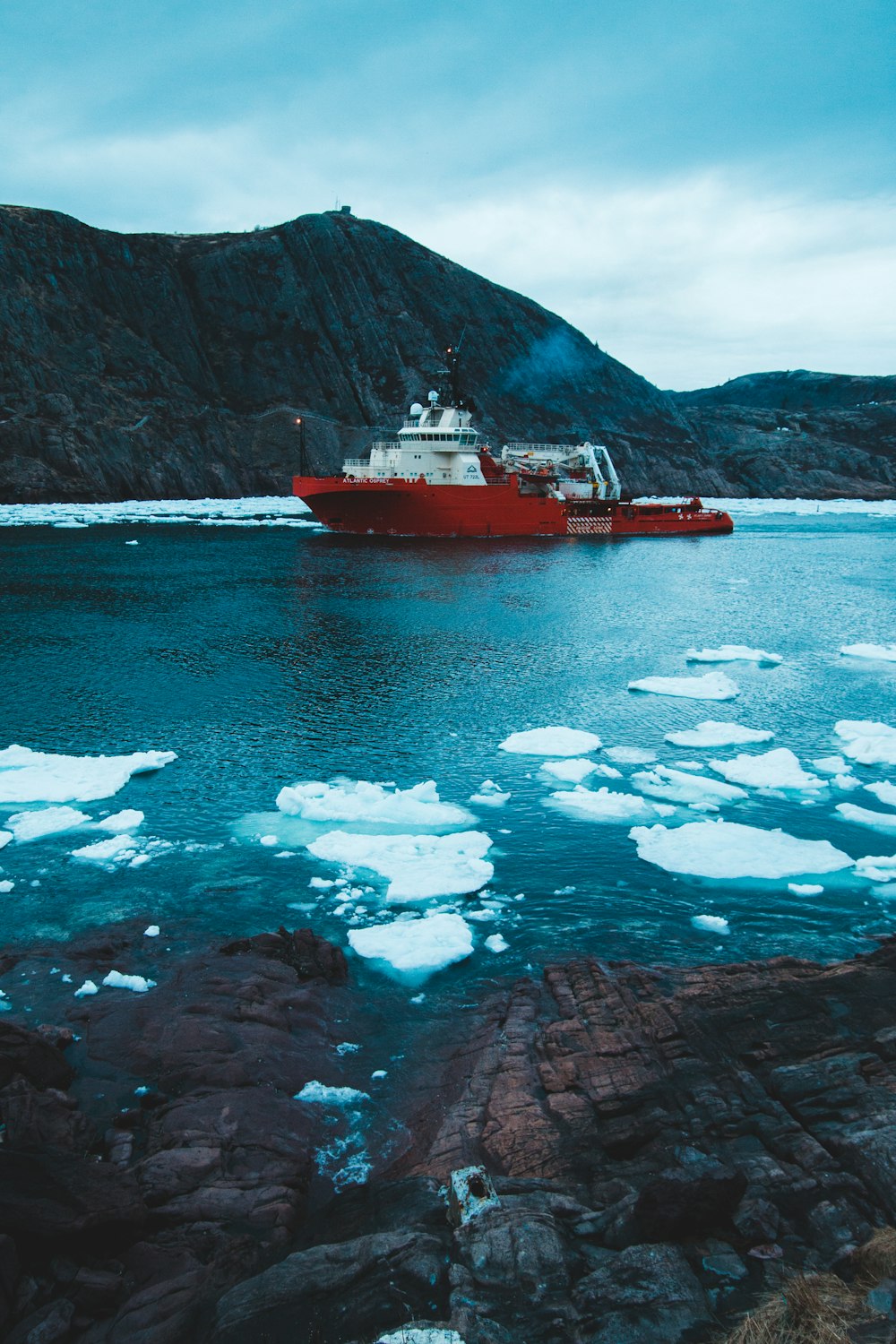 red and white ship\ near hills