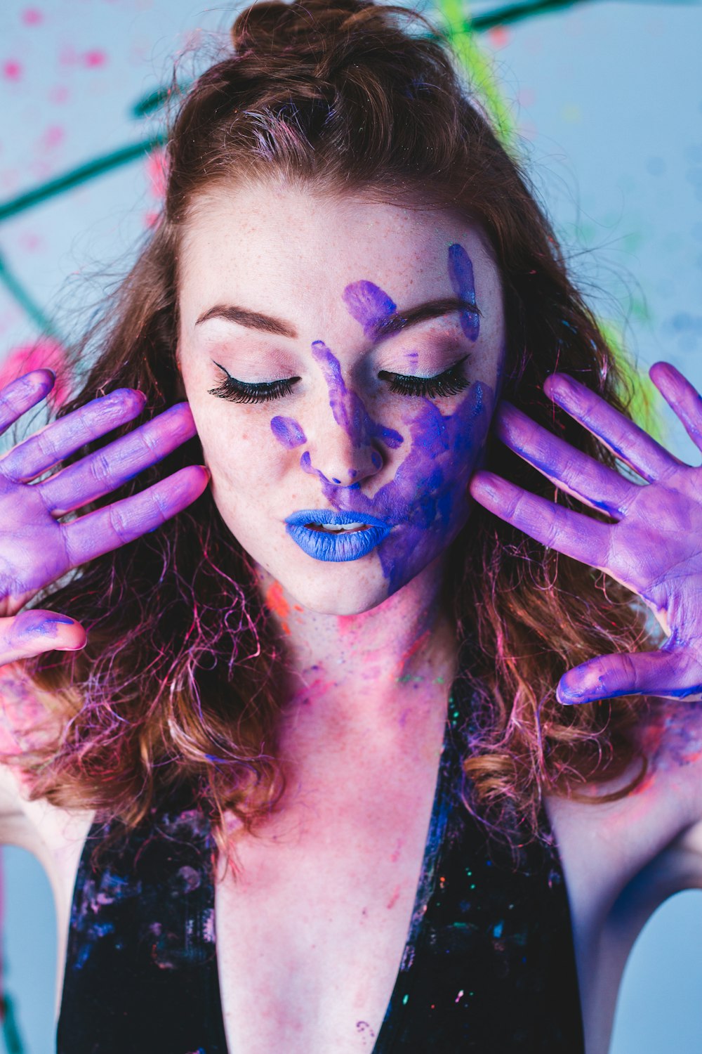 Una donna con vernice viola sul viso e sulle mani