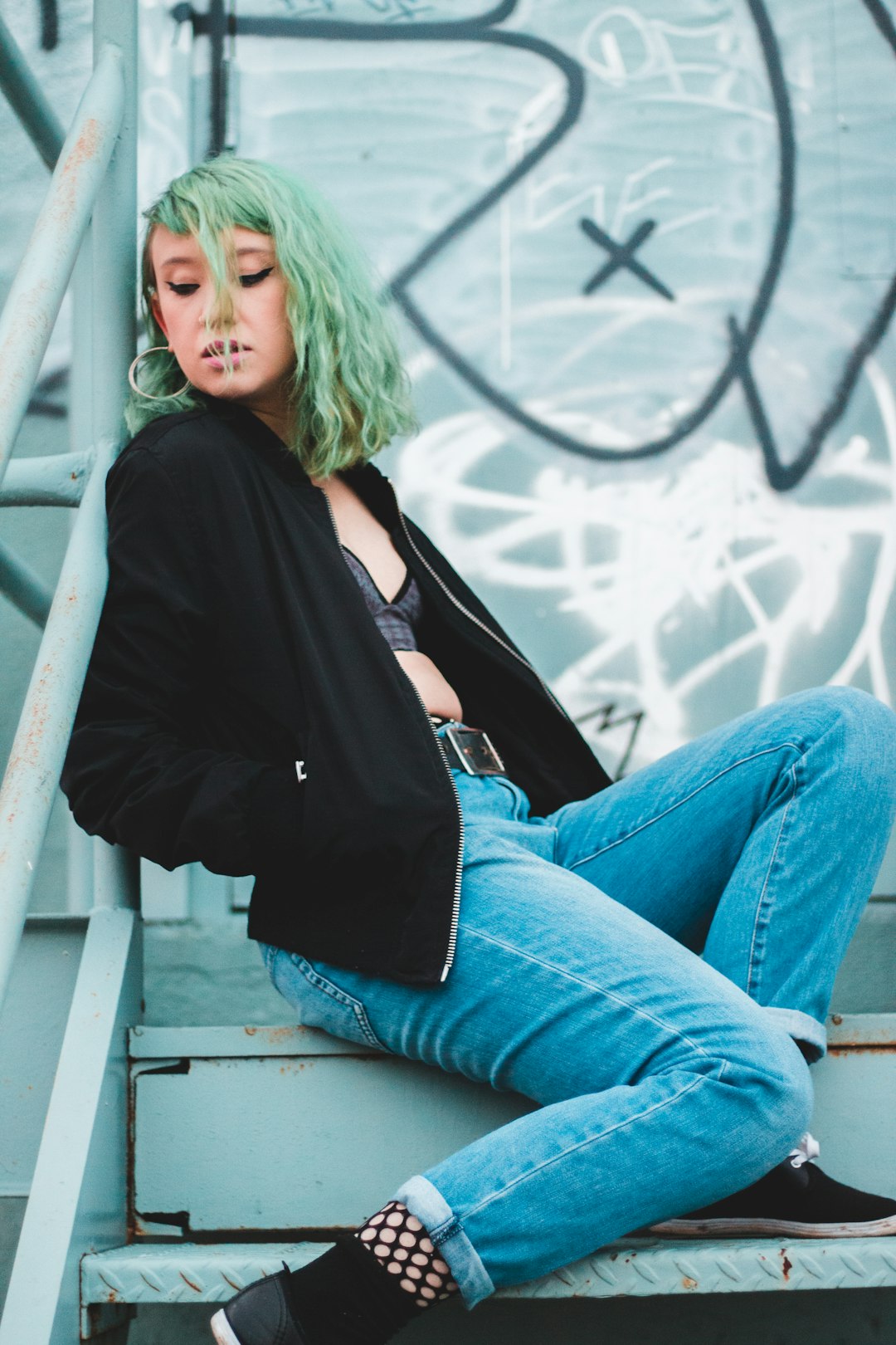 woman wearing black jacket and blue denim jeans sitting on stairs